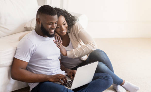 istock Happy black spouses sitting on floor with laptop 1175418234