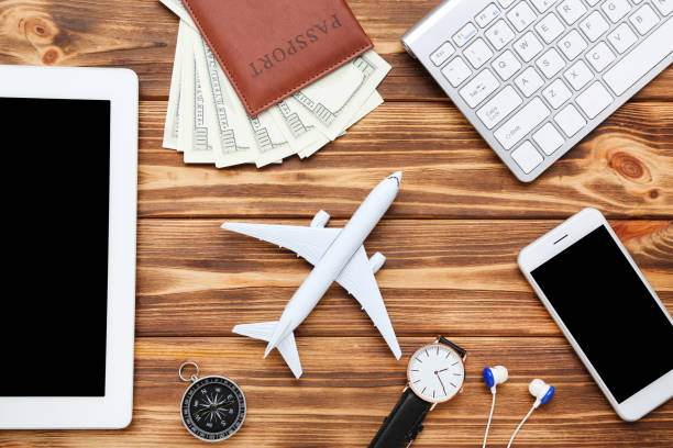 istock Airplane model with keypad, smartphone, dollar banknotes, compass and tablet computer on brown wooden table 1175418246