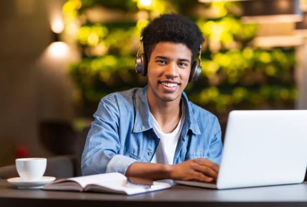 istock Cheerful teen guy with headset working with laptop 1175420081