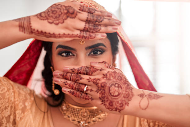 Marry the one who makes your eyes smile Portrait of a beautiful young woman covering her face with her hands on her wedding day MEHNDI stock pictures, royalty-free photos & images