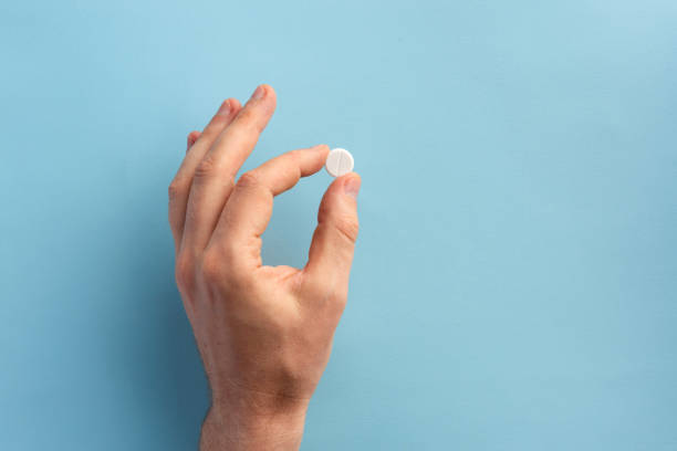 istock Male hand holding one pill. Flat lay. 1175420847