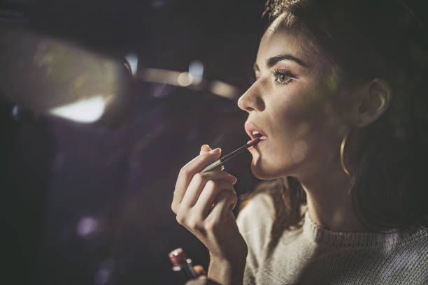 Young beautiful woman applying make-up in the car.