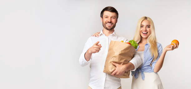 istock Spouses Holding Paper Grocery Bag Pointing Finger At Camera, Panorama 1175423828