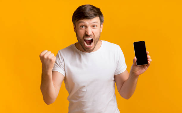istock Excited Man Showing Mobile Phone Screen Shaking Fists, Studio Shot 1175424130