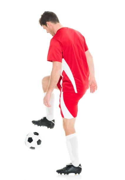 Full length / one man only / one person / side view / profile view of 30-39 years old handsome people caucasian male / mid adult men / mid adult soccer player standing in front of white background wearing soccer uniform who is smiling / happy / cheerful and holding soccer ball / playing soccer - sport / using sports ball / sport / soccer field longitud completa / un hombre solamente / una persona / vista lateral / vista de perfil de 30-39 años de edad gente guapo hombre súcaso hombre / hombres adultos medios / jugador de fútbol adulto medio de pie frente a fondo blanco usando uniforme de fút