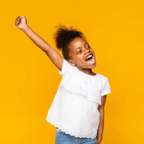 Photo of Cute african toddler girl shouting hooray on orange background