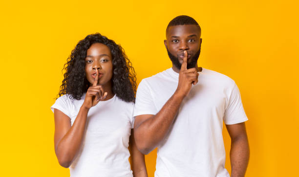 istock Amazed black couple make silence sign, keep forefingers on lips 1175425267