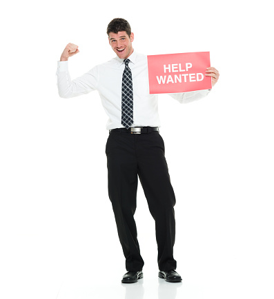 Full length / one man only / one person of 30-39 years old handsome people caucasian male / mid adult men / mid adult business person / businessman standing in front of white background wearing lumberjack shirt / button down shirt / shirt / necktie / pants who is smiling / happy / cheerful / excited / successful and showing fist who is and doing fist pump / showing and holding help wanted sign / sign