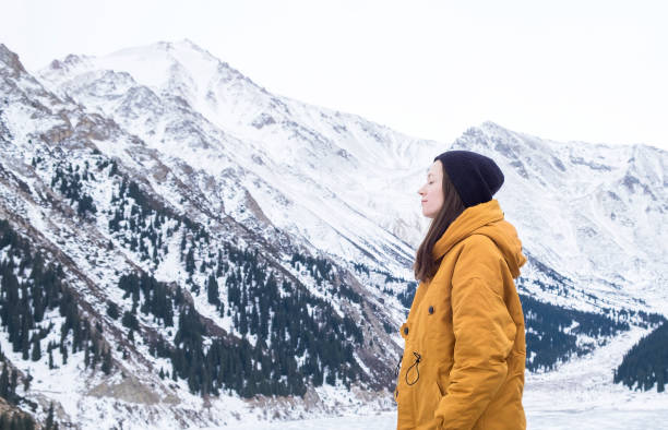 mulher nova com os olhos fechados que respiram profundamente o ar fresco nas montanhas, lago grande de almaty, kazakhstan - lake mountain range mountain deep - fotografias e filmes do acervo