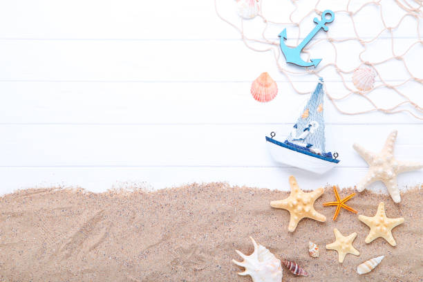 istock Seashells with decorative ship and anchor on white wooden table 1175429175