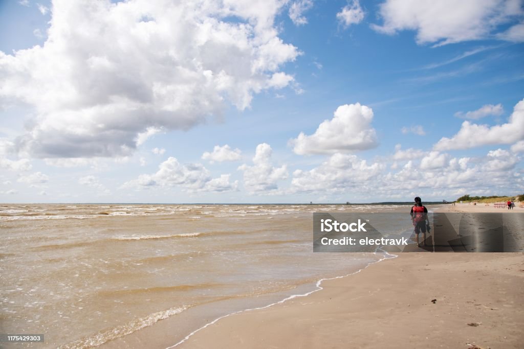 Backpacker walking on the beach in late summer A mid adult man walking on the beach in Parnu in the late summer. 2019 Stock Photo