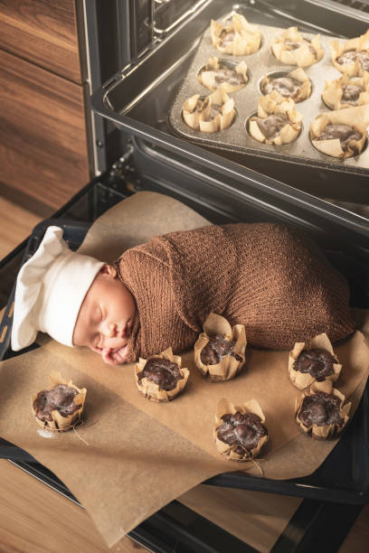 neugeborenes baby trägt kochmütze liegt auf dem ofen tablett mit einem muffins - dreams baby lying on back child stock-fotos und bilder