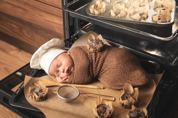 neugeborenes baby trägt kochmütze liegt auf dem ofen tablett mit einem muffins - dreams baby lying on back child stock-fotos und bilder