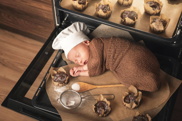 neugeborenes baby trägt kochmütze liegt auf dem ofen tablett mit einem muffins - dreams baby lying on back child stock-fotos und bilder