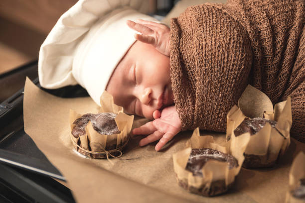 neugeborenes baby trägt kochmütze liegt auf dem ofen tablett mit einem muffins - dreams baby lying on back child stock-fotos und bilder