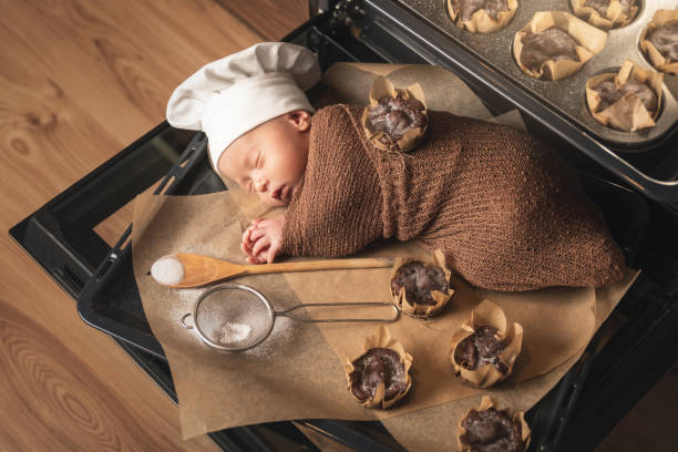 neugeborenes baby trägt kochmütze liegt auf dem ofen tablett mit einem muffins - dreams baby lying on back child stock-fotos und bilder