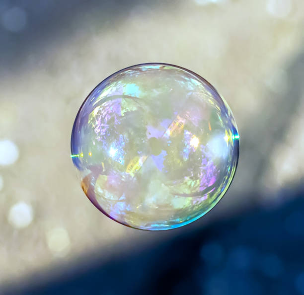 istock Coloured translucent soap bubble floating in the air with reflection of trees, sky and building on sunny evening. 1175431257