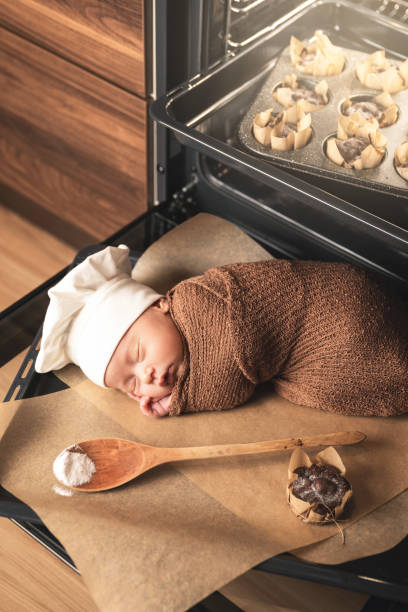 neugeborenes baby trägt kochmütze liegt auf dem ofen tablett mit einem muffins - dreams baby lying on back child stock-fotos und bilder