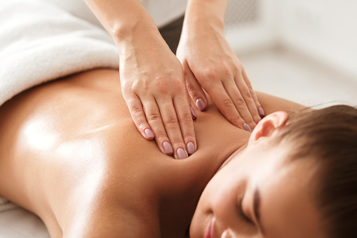 Mujer joven disfrutando de masaje terapéutico de cuello en spa photo