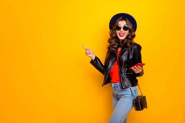 Photo of Portrait of excited shocked surprised girl with wavy hairstyle follow comment promo discount scream wow omg wear black leather jacket isolated over yellow color background
