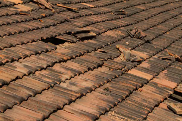 Broken old terracotta rooftiles with hole, traditional cover in India, GOA. Close up. Textured summer background.