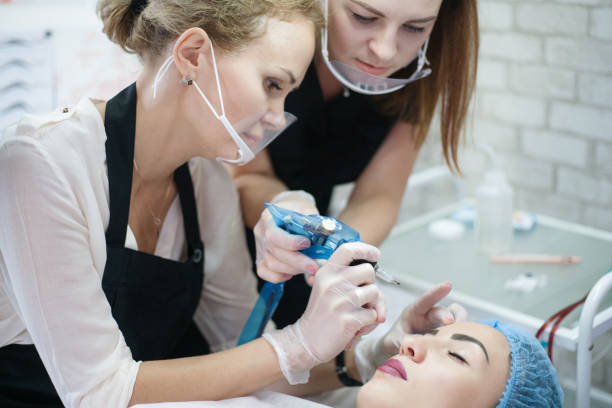 decorative cosmetology practical training eyebrow Decorative cosmetology practical training. Female intern using tattoo machine for eyebrow microblading. microblading apprenticeship stock pictures, royalty-free photos & images