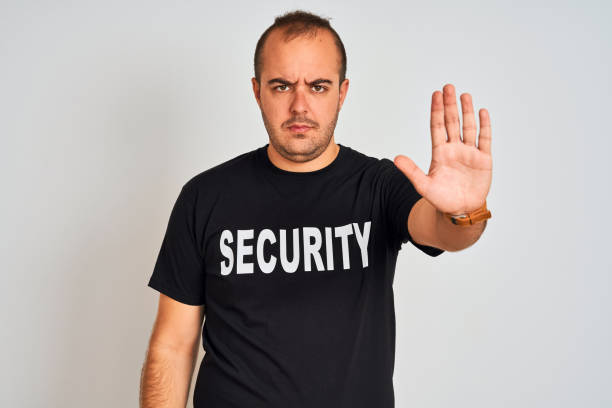 istock Young safeguard man wearing security uniform standing over isolated white background with open hand doing stop sign with serious and confident expression, defense gesture 1175440013
