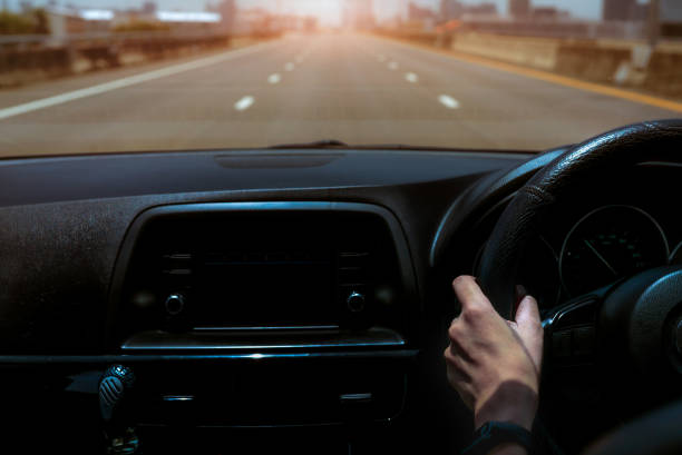 Driver hand holding steering wheel for control car. Inside view of car. Dashboard and windshield. Driving car on concrete road in the city. Perspective view car on highway. Driver hand wear smart band conductor mano sosteniendo el volante para el coche de control. vista interior del coche. tablero y parabrisas. conducir coche en carretera de hormigón en la ciudad. vista de perspectiva coche en la carretera. la mano del conductor lleva la banda intelige
