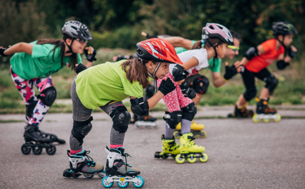 Group of people, man trainer and group of young girls roller skating together on the street.
