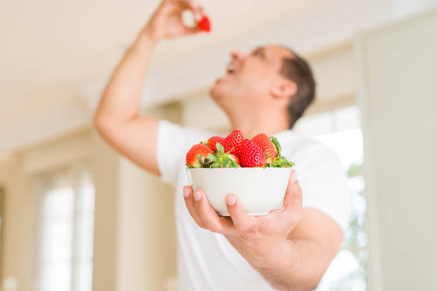 Middle age man eating straweberry at home