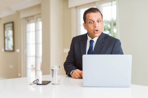 istock Middle age business man working with computer laptop afraid and shocked with surprise expression, fear and excited face. 1175442371