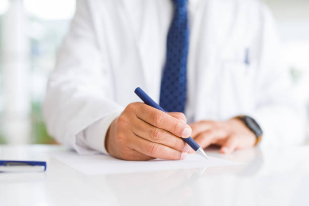 istock Close up of doctor hands writing on paper 1175443403