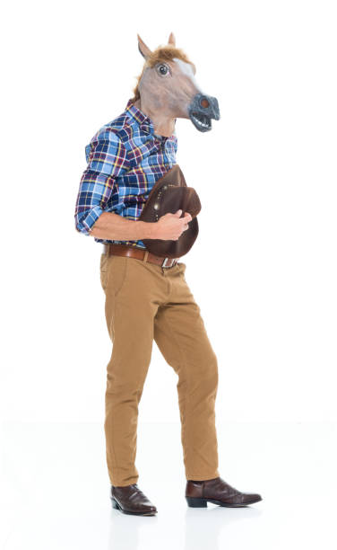 One man only / one person / full length of 30-39 years old adult handsome people caucasian young men / male cowboy standing in front of white background wearing cowboy boot / cowboy hat / hat / mask - disguise / costume / horse costume who is humor / bizarre / horse un hombre solamente / una persona / longitud completa de 30-39 años de edad adulto guapos hombres jóvenes caucásicos / vaquero macho de pie frente a fondo blanco usando bota de vaquero / sombrero de vaquero / sombrero / máscara - disfraz / traje / traj