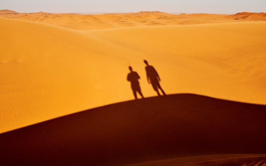 Shot of the silhouettes of two men standing on a hill in the Namibian Desert
