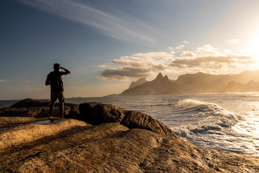 Rio de Janeiro/Rio de Janeiro/Brasil - July, 19 - 2019: Man looking at the Sunset on the Arpoador stone, Arpoador beach in Rio de Janeiro, Brazil