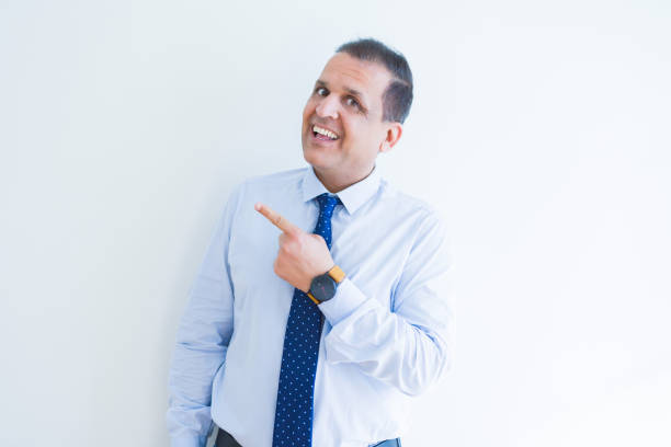 istock Middle age business man smiling and pointing to the side over white background 1175448165