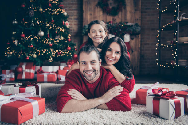 foto von fröhliche optimistischfreundliche familie menschen mama papa schulmädchen trägt rote pullover zu lächeln drinnen feiern weihnachten zusammen - geschenk fotos stock-fotos und bilder