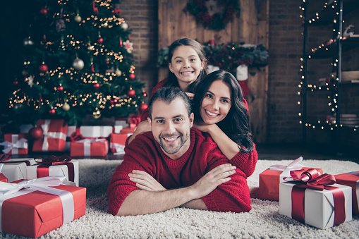 Photo of cheerful optimistic friendly family people mommy dad schoolgirl wearing red sweaters toothily smiling indoors celebrating, christmas together