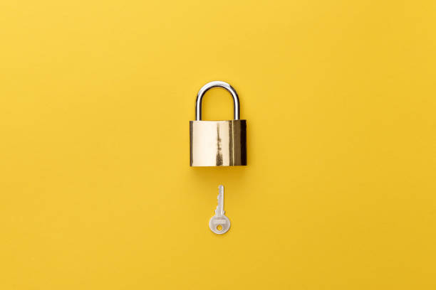 top view of padlock and key on yellow background top view of padlock and key on yellow background locking photos stock pictures, royalty-free photos & images
