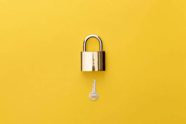 Photo of top view of padlock and key on yellow background