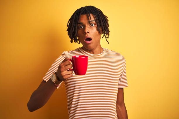 istock Afro american man with dreadlocks drinking a cup of coffee over isolated yellow background scared in shock with a surprise face, afraid and excited with fear expression 1175459085