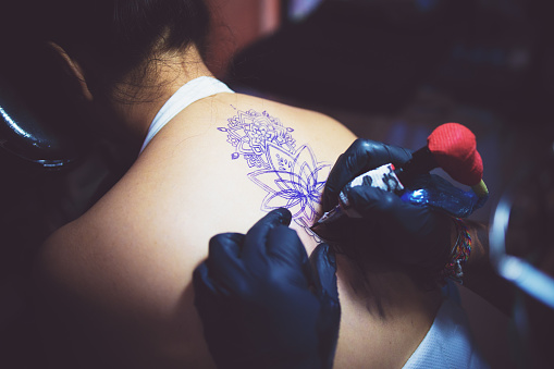 Tattoo, Bali, Lifestyle, Part of a Series - Tattoo Artist Making a Tattoo on Woman's Back using Rotary Tattoo Machine