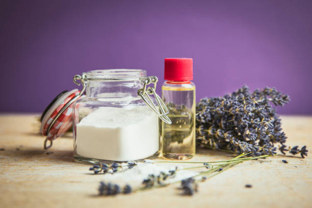 azeite e bicarbonato de sódio esfoliante scrub conceito. cosméticos naturais caseiros da beleza. frasco com pó e frasco do bicarbonato de sódio com azeite, ramalhete da alfazema no fundo roxo. - ground soda baking soda white - fotografias e filmes do acervo