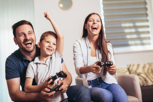 uśmiechnięta rodzina siedząca razem na kanapie grając w gry wideo - sofa indoors childhood technology zdjęcia i obrazy z banku zdjęć