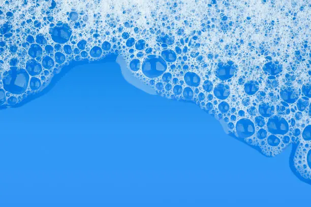 Photo of Bubble foam soap shampoo on blue water surface texture background top view