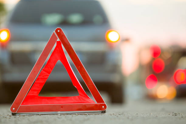 istock Red emergency triangle stop sign and broken car on a city street. 1175475657