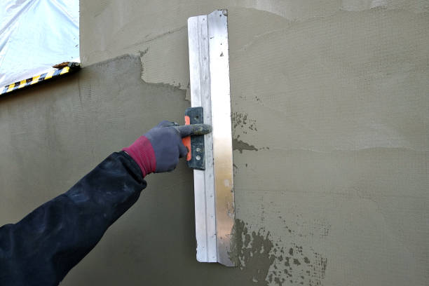 istock Worker covering insulated wall with solution of glue over plastered styrofoam insulation. 1175475763