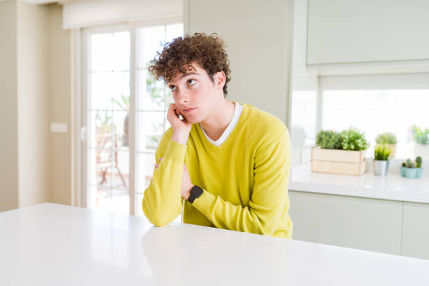 istock Young handsome man wearing yellow sweater at home thinking looking tired and bored with depression problems with crossed arms. 1175476033