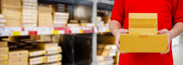 istock Delivery man carrying boxes in front of blur warehouse background 1175477577