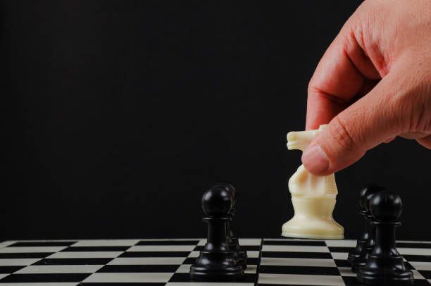 istock Hand man making move with white horse (knight) on chess board 1175477960